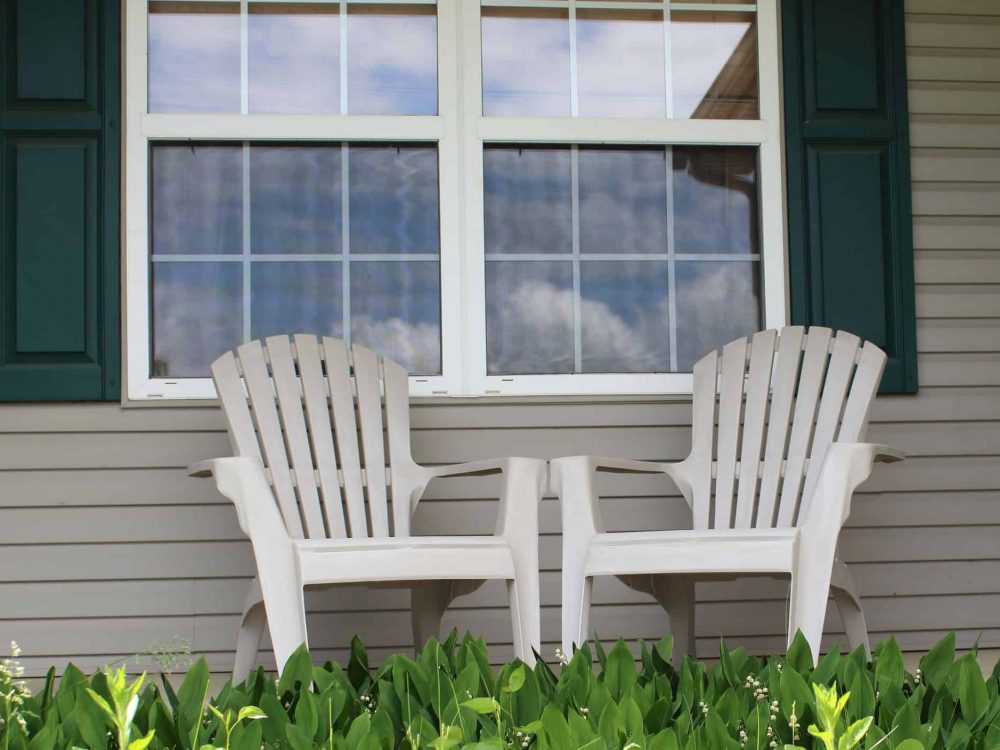 Chairs on a porch with the sky reflecting in the windows