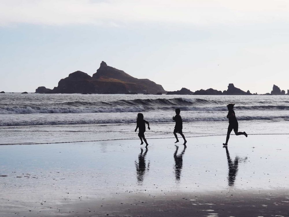 Children running on beach in silhouette.