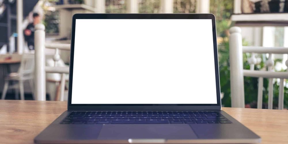 Mockup image of laptop with blank white desktop screen on wooden table