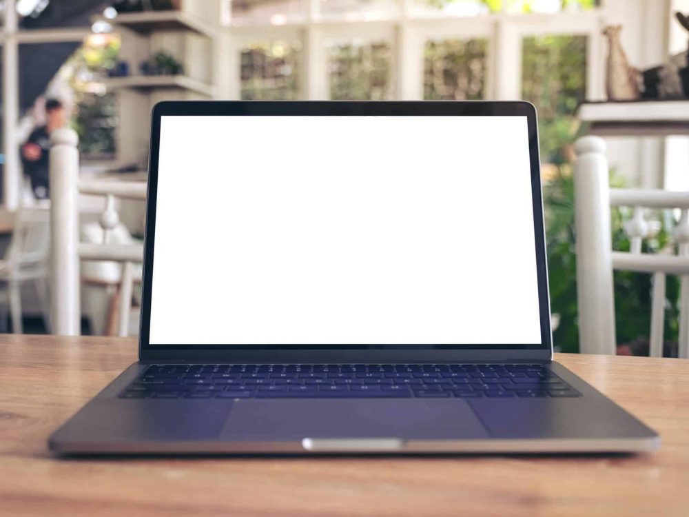 Mockup image of laptop with blank white desktop screen on wooden table